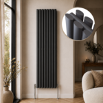 Alma Double Oval Vertical Designer Radiator 1600mm x 360mm in Anthracite installed in a modern beige living room with herringbone flooring and contemporary décor.