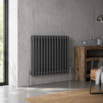 Anthracite horizontal column radiator installed in a modern living space with wooden flooring and neutral décor.