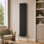 Aura 2 Column Vertical Radiator 1800x380mm Anthracite installed in a modern neutral living room with shelving and wooden flooring.