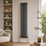 Aura 2 Column Vertical Radiator 1800x425mm Anthracite installed in a modern living room with neutral décor and wooden flooring.