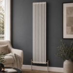 Aura 2 Column Vertical Radiator 1800x470mm White installed in a modern living room with dark feature wall and wooden flooring.