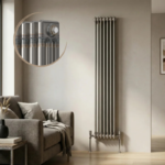 Aura 3 Column Vertical Radiator 1800x335mm Raw Metal installed in a modern living room with close-up inset highlighting the premium raw metal finish.