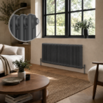 Aura 2 Column Horizontal Radiator 600mm x 1415mm Anthracite installed beneath a large black-framed window in a contemporary living room with a close-up inset showcasing the smooth anthracite finish and premium column design.