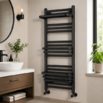 Matt black heated towel rail installed in a monochrome bathroom with white towels for contrast