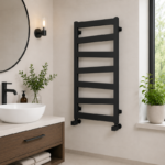 Compact matt black ladder towel radiator installed in a small stylish bathroom with a white towel