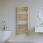Vela brushed brass heated towel rail (1200mm x 500mm) installed in a contemporary bathroom setting with a soft brushed brass finish, showcasing its elegant vertical design and premium styling.